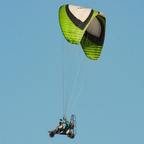 Paratrike da Voar a Norte com asa verde em voo contra o céu azul